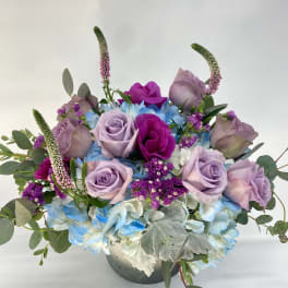 Lavender roses and blue hydrangeas in a low vase arrangement