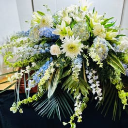 Large white and blue floral casket spray with cascading blooms