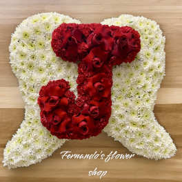 Angel-shaped cushion of white flowers with a red rose letter J on top