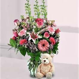 Its a Girl. Girl color flowers arranged in a vase and teddy bear.