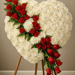 Heart-shaped standing spray of white roses with a diagonal cascade of red roses.