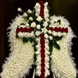 Standing sympathy piece shaped like angel wings with white mums and a red and white rose cross