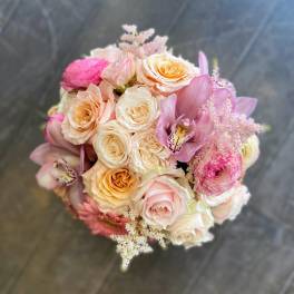 Bouquet of blush and peach roses with pink orchids and soft filler flowers