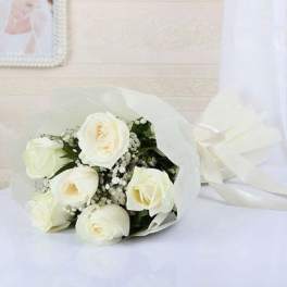 White rose bouquet wrapped in white paper with a ribbon