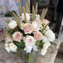 Blush and white rose bouquet in a green glass vase
