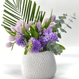 Lavender tulips and purple hyacinths in a white textured vase