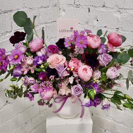 Pink and purple mixed bouquet in a white vase with a ribbon