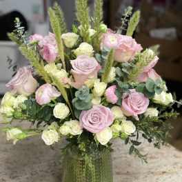 Pink and white roses arranged in a green glass vase