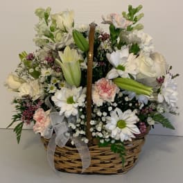 Basket arrangement of white flowers with pink accents and a ribbon bow