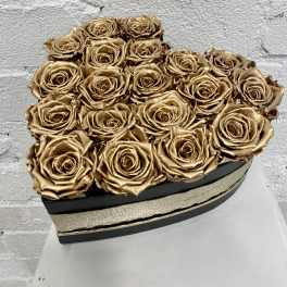 Gold roses arranged in a black heart-shaped box