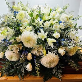 Large white floral spray on a wooden casket