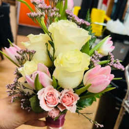 Hand-tied bouquet of cream roses, pink roses, and pink tulips wrapped with pink and ivory ribbon