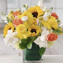 Bouquet of yellow sunflowers and roses in a glass vase