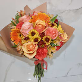 Bouquet of orange, pink, and yellow flowers wrapped in brown paper