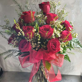 Red roses in a clear glass vase with a pink ribbon