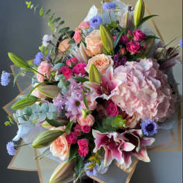 Large bouquet of pink lilies, roses, hydrangea, and blue accent flowers