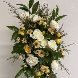 Standing spray of white roses and yellow flowers on a metal easel