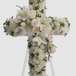 White floral cross arrangement with lilies and roses on an easel