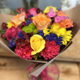 Bright mixed bouquet of roses, carnations, and daisies with butterfly picks