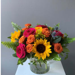 Bouquet of bright roses and sunflowers in a clear glass vase