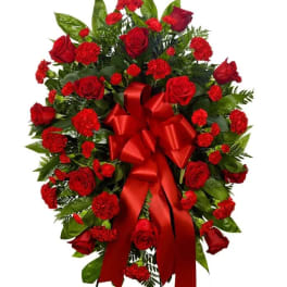 Red rose and carnation standing spray with a large red ribbon