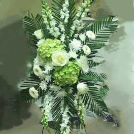 Standing floral spray with white flowers and green hydrangeas on an easel
