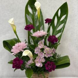 Basket arrangement with pink and purple flowers and white calla lilies