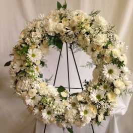 White floral wreath on a black stand