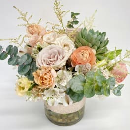 Mixed pastel bouquet in a glass vase with eucalyptus and succulents
