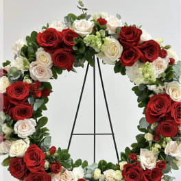Circular wreath of red and white roses on a black stand
