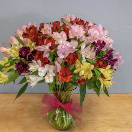 Mixed bouquet of colorful alstroemeria in a glass vase with a pink ribbon