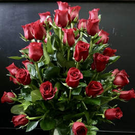 Tall arrangement of long-stemmed red roses in a clear glass vase