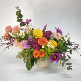 Mixed bouquet of roses and purple daisies in a round vase