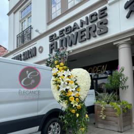 Standing floral heart arrangement with white blooms and yellow roses on an easel