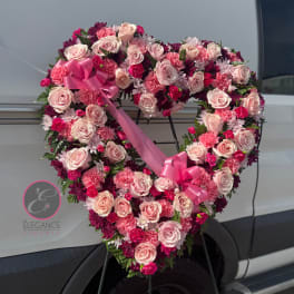 Heart-shaped floral wreath of pink roses and carnations with a ribbon bow