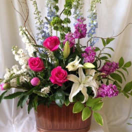 Tall mixed floral arrangement with pink roses and white lilies in a copper container