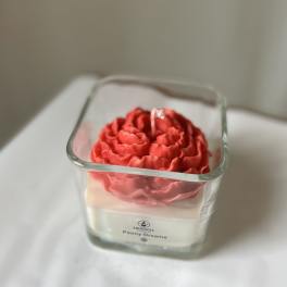 Red flower-shaped candle in a square glass container
