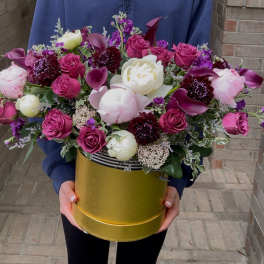 Large bouquet of pink and white flowers in a gold hatbox