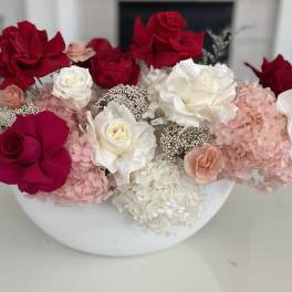Red and white roses with pink hydrangeas in a white bowl