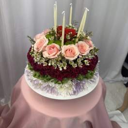Round floral cake with pink roses and tall white candles
