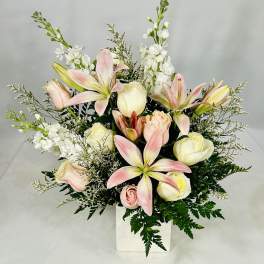 Pink lilies and cream roses in a white vase