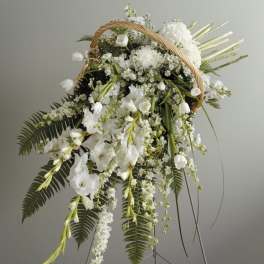 Tall standing basket spray of cascading white flowers with ferns on an easel