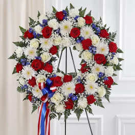 Circular standing wreath of red, white, and blue flowers on an easel