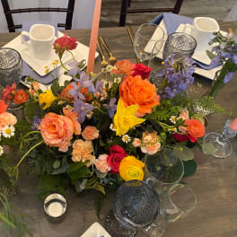 Colorful floral centerpiece with roses, daffodils, and purple blooms on a table