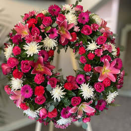 Standing wreath of pink lilies, roses, gerbera daisies and white chrysanthemums on an easel