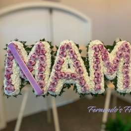Standing floral tribute spelling MAMA with pink roses and white flowers on easels