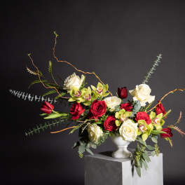 Red and white roses with green orchids in a white vase