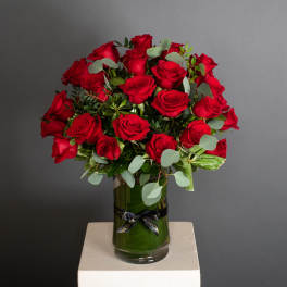 Red roses arranged in a glass vase with eucalyptus