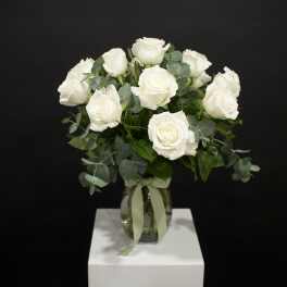 White rose bouquet in a glass vase with ribbon