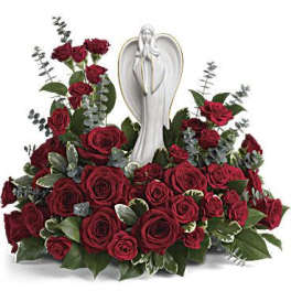 Low arrangement of red roses surrounding a white angel figurine